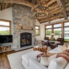 a living room with couches, chairs and a fire place in front of a stone fireplace