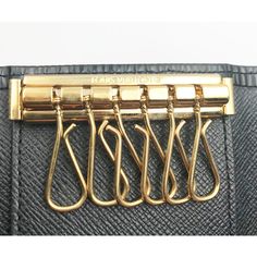 four gold metal clips are attached to a black purse