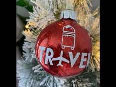 a red ornament with the word travel on it hanging from a christmas tree