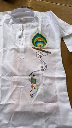 a white shirt with an image of a peacock on the front, and a feather painted on the back