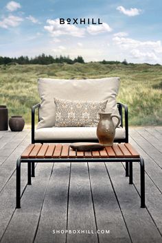 An outdoor lounge chair with light brown cushion and black frame with a wooden top outdoor lounge table set on a wooden deck patio beside grassy field Outdoor Gathering Space, Dining Outdoor, Modern Outdoor Living, Modern Outdoor Chairs, Gathering Table, Lounge Chair Cushions, Outdoor Living Design, Outdoor Lounge Chair, Black Steel Frame