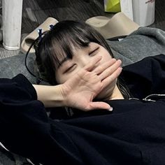 a woman covering her face with her hands while laying on a bed in a room