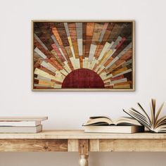 an open book sitting on top of a wooden table next to a framed painting above it