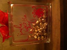 a glass container with some gold bells in it and a red bow on the top