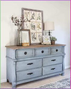 a blue dresser with flowers and pictures on top