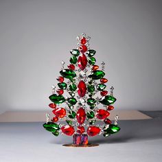 a small christmas tree with red, green and white ornaments on it's base