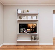 an entertainment center in the corner of a room with wood flooring and white walls