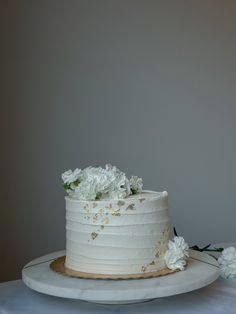 there is a white cake with flowers on the top and bottom, sitting on a table