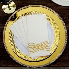 the place setting is set with gold and white plates, napkins, and silverware