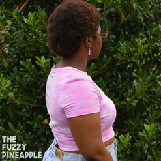 a woman in pink shirt standing next to bushes