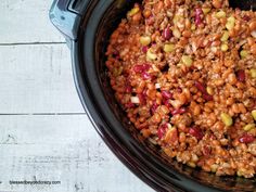 a crock pot filled with beans and other food sitting on top of a wooden table