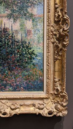 a painting hanging on the wall in front of a frame with flowers and trees painted on it