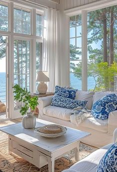 a living room filled with furniture and large windows overlooking the water in front of it