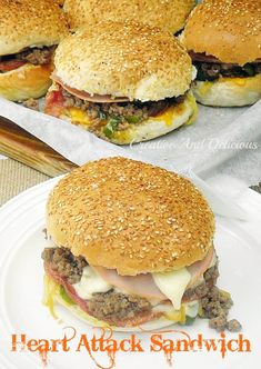 four hamburgers sitting on top of a white plate next to a tray of cheeseburgers