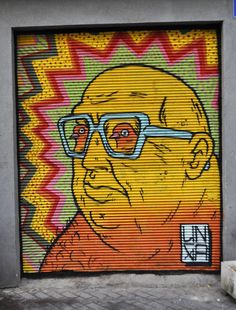 an image of a man with glasses painted on the side of a garage door in front of a building