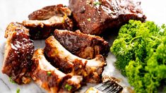 some meat and broccoli on a plate with a fork in the foreground