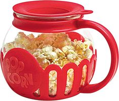 a glass jar filled with popcorn on top of a white table next to a red lid