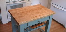 a kitchen island with a cutting board on it's side in front of an oven