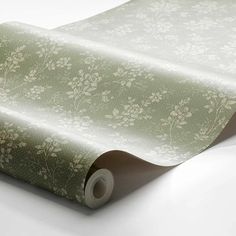 a roll of green and white wallpaper with flowers on the side, in front of a