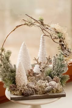 a white cake plate topped with pine cones and snow covered trees