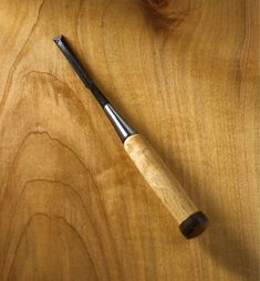 a pen sitting on top of a wooden table next to a piece of wood that has been cut in half