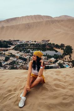 a woman sitting on top of a sand dune