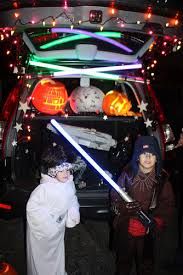 two children dressed up as star wars characters in front of a car with lights on