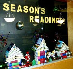 a window display with books and ornaments in the front, behind which is a sign that says season's reading