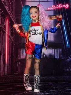 a woman with blue hair and tattoos holding a hot dog in her hand while standing next to a neon sign