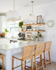 a kitchen with white counter tops and wooden chairs