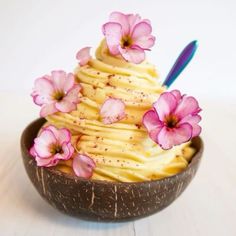 a bowl filled with yellow frosting and pink flowers