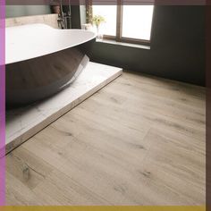 a bathtub sitting on top of a wooden floor next to a window in a bathroom