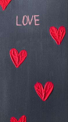 the word love is written on a chalkboard with red hearts and leaves drawn on it