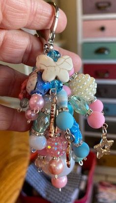 a hand holding a keychain with charms on it's sides and beads hanging from the end