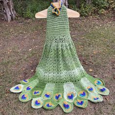 a green crocheted dress with peacock feathers on it