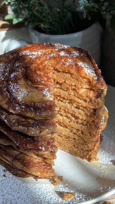 a stack of pancakes sitting on top of a white plate covered in powdered sugar