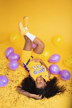 a woman laying on the ground with balloons and confetti all over her body