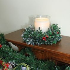 a candle is sitting on top of a table with christmas wreaths and wrapped presents