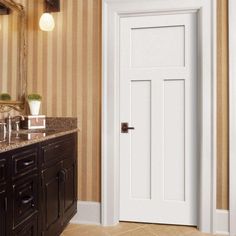 a white door in a bathroom next to a vanity and mirror with lights on it