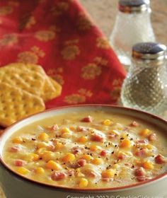 a bowl of corn chowee with crackers on the side