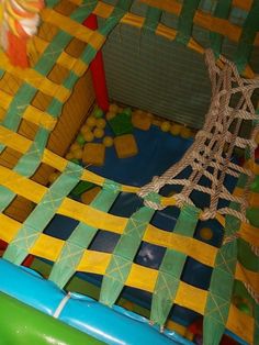 an inflatable obstacle with ropes and balls on the ground at a children's play area