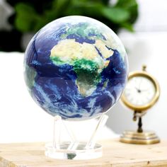 the earth globe is sitting on a stand next to a clock