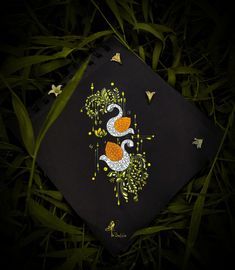 a black notebook with an orange and white bird on it sitting in the green grass