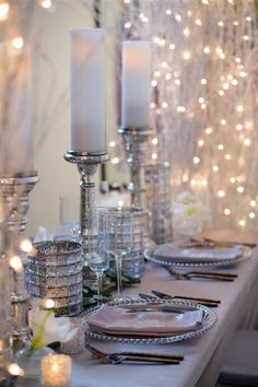 the table is set with candles, plates and silverware