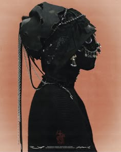 a woman wearing a black hat with chains around her neck and an animal's head