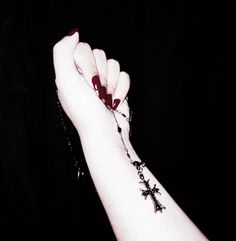 a woman's arm with a rosary and cross tattoo on her left wrist,