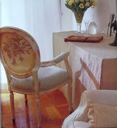 a chair sitting on top of a hard wood floor next to a table with flowers