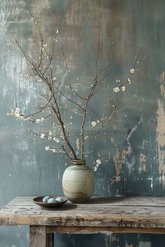 a vase with some flowers in it sitting on a wooden table next to two eggs