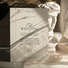 a wedding card sitting on top of a table next to a statue