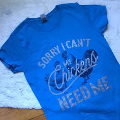 This Tee Shirt Had Me At “My Chickens Need Me”. For All The Chicken Parents Out There, Both Farm And Suburbs Alike, This One’s For You. In Nwot Euc Like New Condition, A Teal Or Turquoise Blue Tee Shirt (My Camera Makes The Color Appear Darker Than It Actually Is) In A Size Small. 100% Cotton. The Font Is Silver And The Very Detailed Illustrations Of Chickens In Back Are A Black Or Very Dark Blue Color. You Can See Feathers And The Eyes On The Faces Of The Chickens. This Gildan Tee Is A Heavy Cotton, Like The Label Says. Measures Pit To Pit 16.5” Length 26.5” Silver Casual T-shirt With Letter Print, Silver Short Sleeve Graphic Tee, Casual Silver T-shirt With Letter Print, Casual Silver Tops With Graphic Print, Casual Silver Top With Graphic Print, Silver Graphic Print Cotton Top, Silver Cotton Top With Graphic Print, Silver Cotton Tops With Graphic Print, Blue Tee